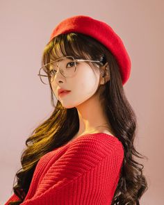 a woman wearing glasses and a red hat is posing for the camera with long hair