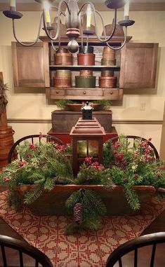 a christmas centerpiece with pine cones, greenery and other holiday decorations on a dining room table