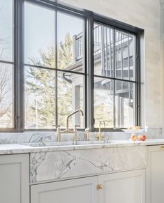 a kitchen with marble counter tops and white cabinets, along with an open window that looks out onto the street