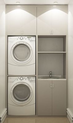 a washer and dryer in a small room with cabinets on the wall behind them