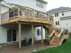 a wooden deck with stairs leading up to the upper floor and second story patio area