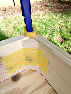 a piece of wood with yellow paint on it and a blue object sticking out of the corner