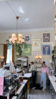 people are standing in the kitchen area of a restaurant with pictures on the wall and ceiling