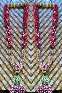 two red and white beaded necklaces are hanging on a wall next to each other