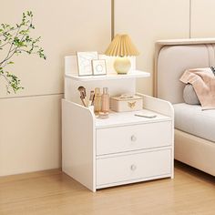 a bedroom with a bed, nightstand and plant on the side table next to it