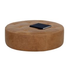 a round ottoman with a book on top