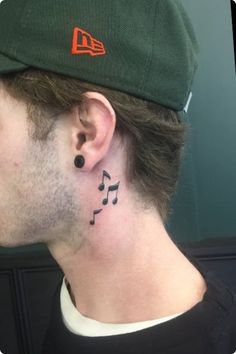 a man with a music note tattoo on his ear and behind his ear is a baseball cap