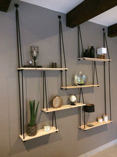 three shelves with plants, candles and other items on them against a wall in a living room