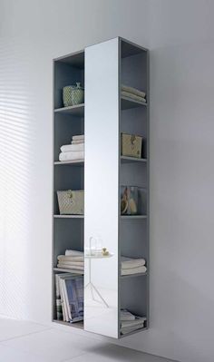 a tall mirrored cabinet with shelves in the corner