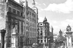 an old black and white photo of a city street with tall buildings on both sides