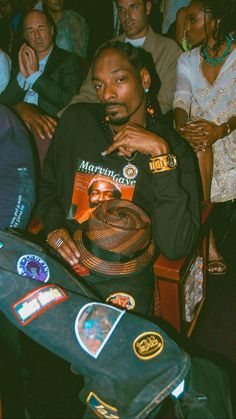 a man sitting in front of a group of people with badges on his shirt and hat