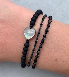 two bracelets with black beads and a mother's day heart charm on the wrist