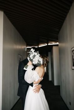 a bride and groom are kissing in an empty hallway at the end of their wedding day