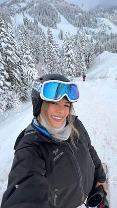 a woman with skis and goggles on posing for a photo in the snow