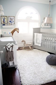 a baby's room is decorated in blue and white with a giraffe on the rug