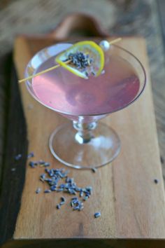 a drink in a wine glass with a lemon slice on the rim and lavender sprinkles