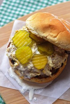 a sandwich with pickles on it sitting on top of a piece of wax paper