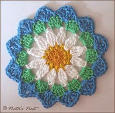 a crocheted doily with a white and yellow flower on it's center