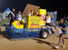 some people are standing in the back of a truck decorated with toys and letters on it