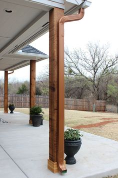 a wooden post on the side of a house with potted plants next to it