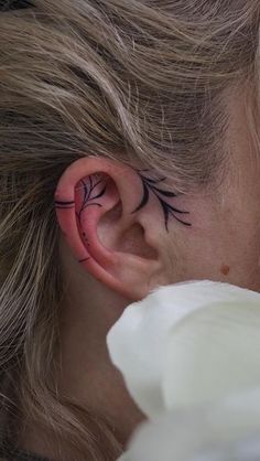 a close up of a person's ear with tattoos on their ears and behind the ear