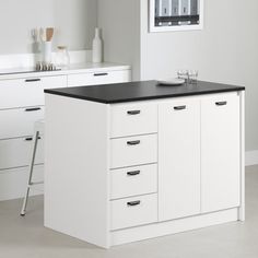 a kitchen with white cabinets and black counter tops in front of a window on the wall