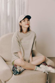 a woman sitting on top of a chair wearing a baseball cap and socks with her legs crossed