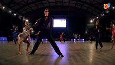 a group of people dancing on top of a wooden floor in front of a screen