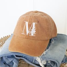 a brown hat with the letter m on it sitting on top of some blue jeans