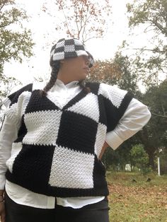 a woman is wearing a black and white crochet sweater with a hat on her head