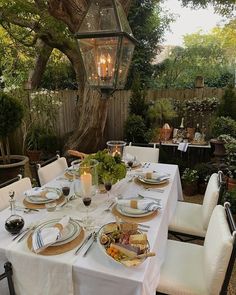 an outdoor dining table set with plates and silverware