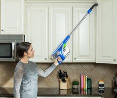 a woman is using a handheld vacuum cleaner on the kitchen counter