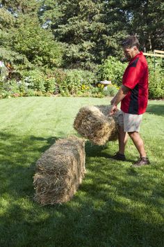 a man standing in the grass with two hay bales