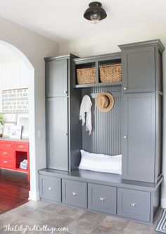 the entryway is decorated in gray and white with red drawers, baskets, and a coat rack