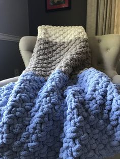 a blue and white crocheted blanket sitting on top of a chair