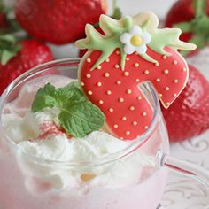 a strawberry milkshake with whipped cream and strawberries in the background