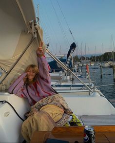 a woman sitting on the back of a sailboat with her arms up in the air