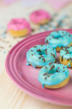 a pink plate topped with donuts covered in blue frosting and sprinkles