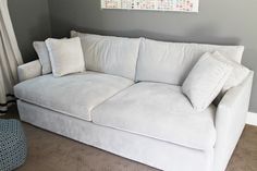 a white couch sitting in a living room next to a window