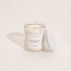 a candle that is sitting next to a white container with a lid on the table