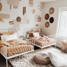 two twin beds in a bedroom with wallpaper and pillows on the walls, next to each other