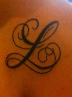 a tattoo on the back of a woman's shoulder with an l in it