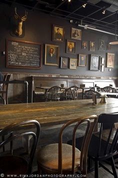 an empty restaurant with wooden tables and chairs in front of pictures on the wall above them