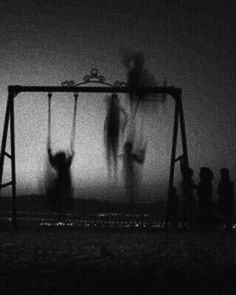 some people are hanging upside down on a swing set in the foggy night sky