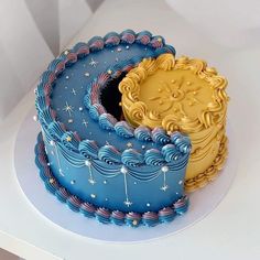 a blue and yellow cake sitting on top of a white table next to each other