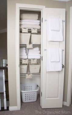 an organized closet with white towels and baskets