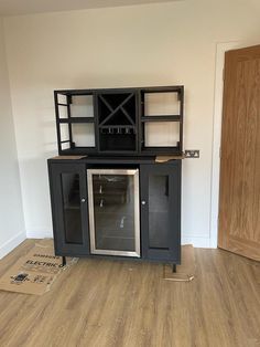 an empty room with a black cabinet and wooden floors