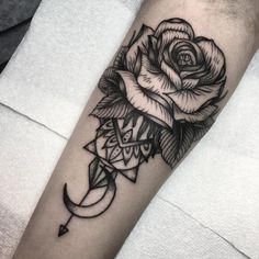 a black and white rose tattoo on the left forearm, with an arrow in the middle