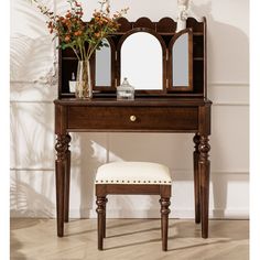 a wooden vanity with mirror, stool and flowers in vase next to it on the floor