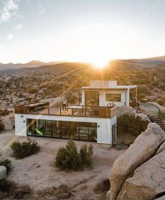 an aerial view of a house in the middle of desert with mountains and rocks surrounding it